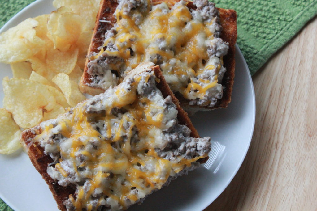 Beef stroganoff sandwich with chips on a white plate