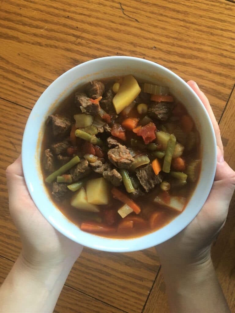 Hands holding a bowl of Vegetable Beef Soup