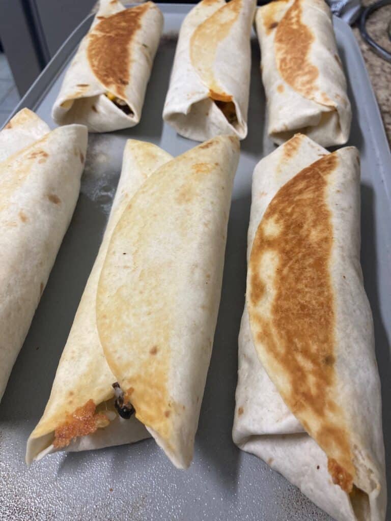 Crispy Chicken, Rice and Bean Burritos on a griddle.